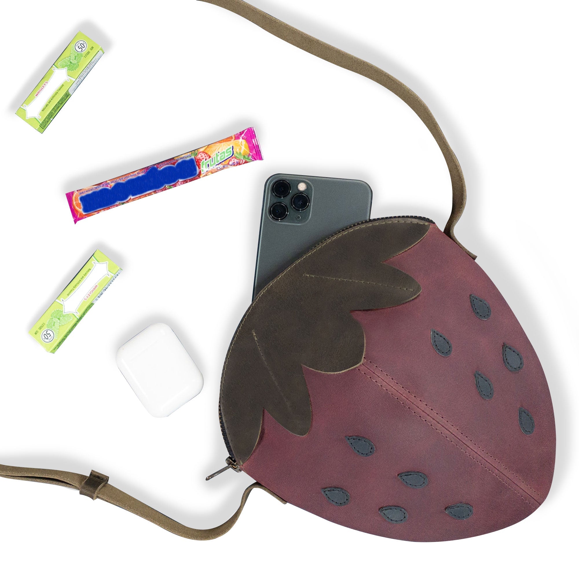 Leather Strawberry-Shaped Shoulder Bag by Tudi Frudi, showcasing the interior with a smartphone and treats. This Full Grain Leather crossbody bag combines functional design with artisanal beauty. Handmade in La Antigua Guatemala & Oaxaca Mexico, it is part of a small batch production that is hand cut and hand sewn.