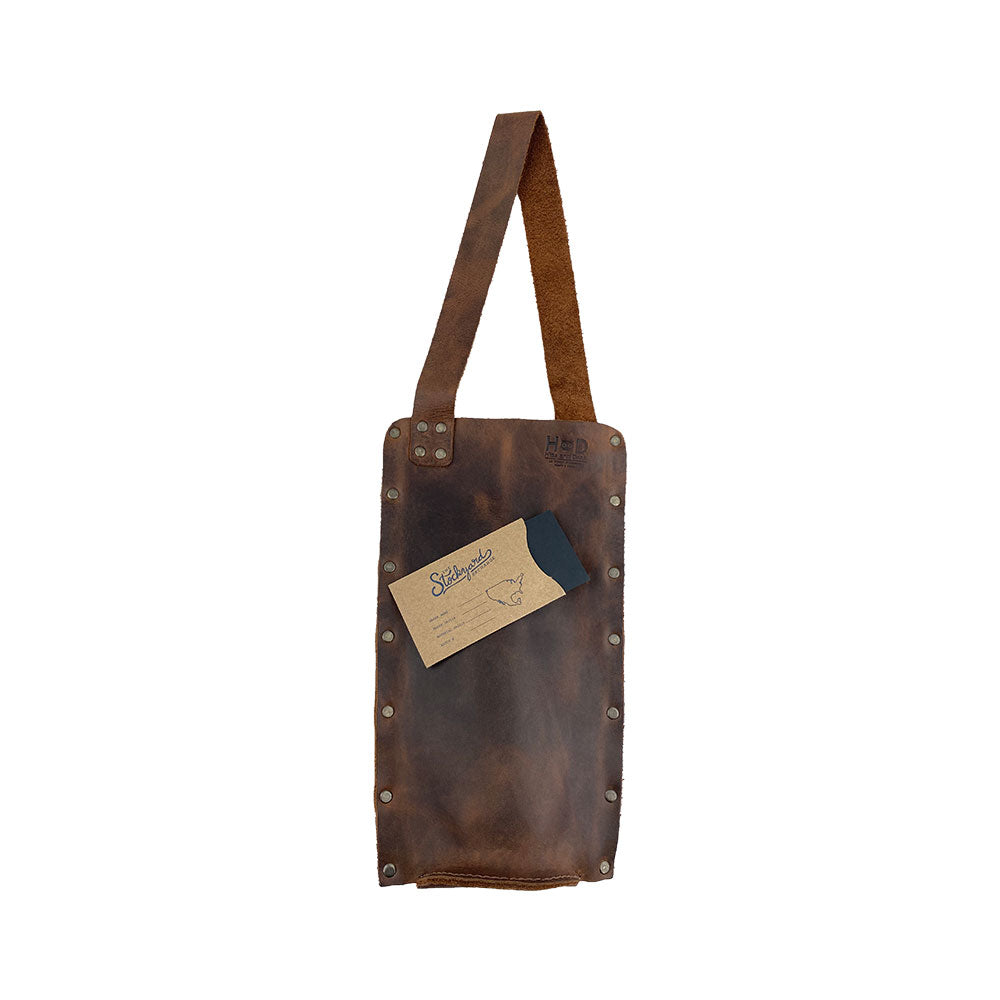 Rustic Wine Carrier For Standard 750ml Bordeaux Bottle by Hide & Drink, featuring a tag that highlights its artisan quality. This Single Wine Carrier made from Full Grain Leather showcases the essence of small batch production, hand cutting, and hand sewing, all fire branded and handcrafted in La Antigua Guatemala & Oaxaca Mexico.