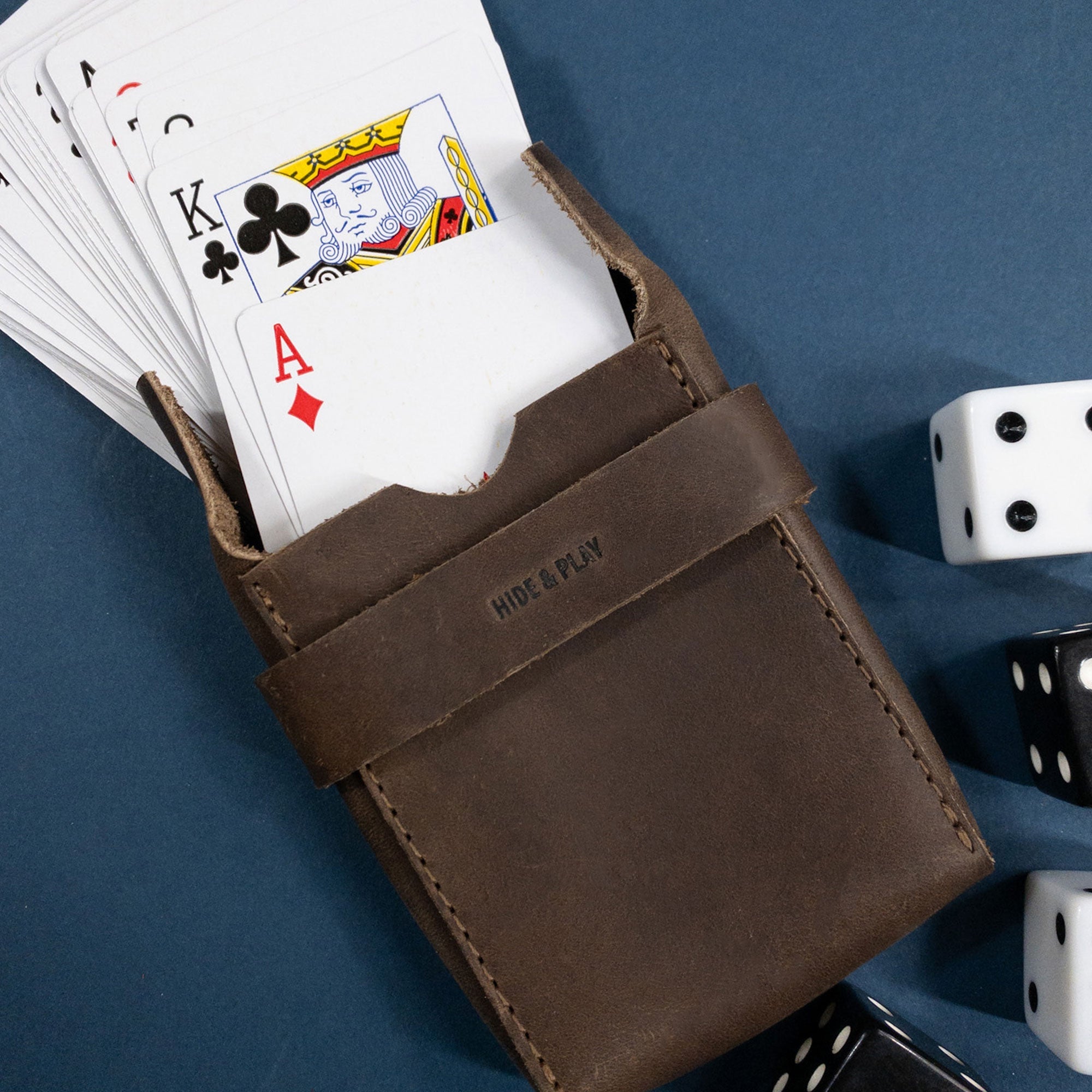 Hide & Drink's Playing Card Case holding a deck of cards, ideal for secure storage. This classic case for playing cards (not included) doubles as a travel accessory with its durable full grain leather. Artisan-crafted in small batches, showcasing hand cut and fire branded details from StockyardX, it's perfect for card enthusiasts.