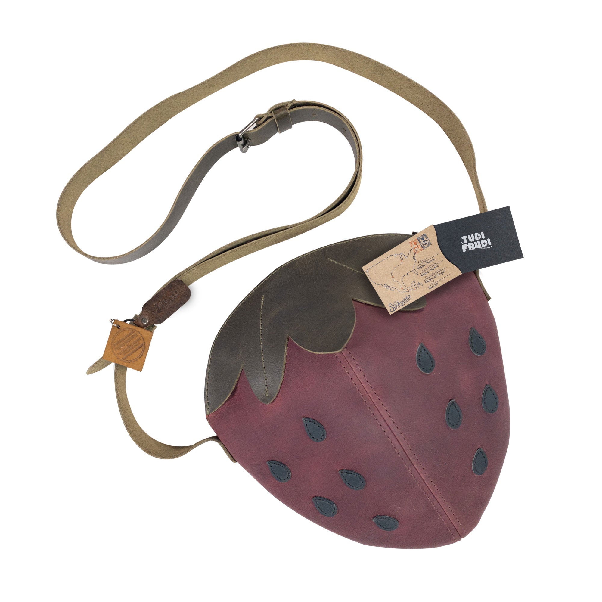 Finished Leather Strawberry-Shaped Shoulder Bag by Tudi Frudi with tags showcasing its artisanal roots. Made from Full Grain Leather, it illustrates the commitment to small batch production, hand-cut and hand-sewn craftsmanship, and is proudly handmade in La Antigua Guatemala & Oaxaca Mexico.