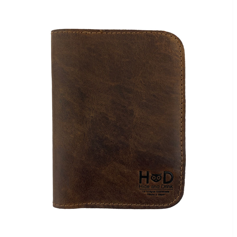 Front of the Hide & Drink Travel Wallet, embodying a sleek vintage style. This travel wallet is a stylish bifold passport case, perfect for holding cards and cash, handcrafted from full grain leather in La Antigua Guatemala.