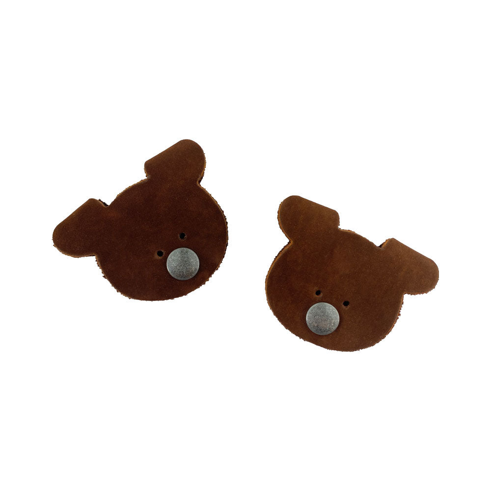 A pair of Bear Shaped Cord Keepers (Cord Clam) by Hide & Drink, featuring unique designs in Full Grain Leather, handmade and fire branded, perfect for keeping cords organized. Artisan crafted in La Antigua Guatemala & Oaxaca Mexico. Small Batch Production.